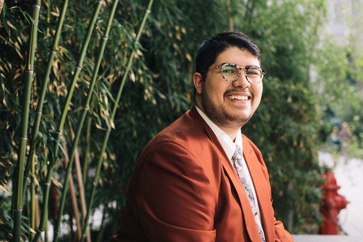 student David Spicer smiling in front of lush greenery