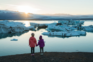 Children holding hands looking at melting ice caps