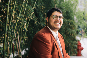 student David Spicer smiling in front of lush greenery